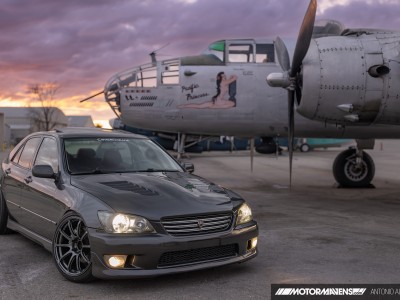 Lexus IS300 with Advan RSII wheels and Chargespeed vented CF hood parked in front of Pacific Princess B25 bomber Doolittle Raid aircraft at airport hangar